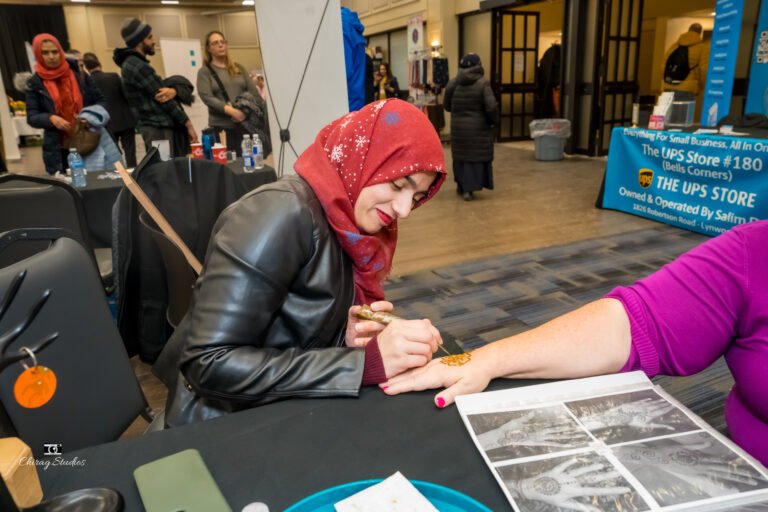 Henna artist at work with a guest at the expo